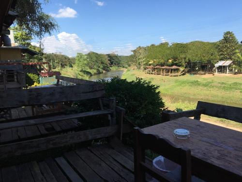 a wooden deck with a table and a view of a river at Golden Hut -Chill Bungalows in town黄金泰式传统独栋小屋 in Pai