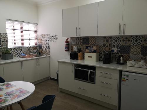 a kitchen with white cabinets and a table in it at INBLOEM in Bloemfontein