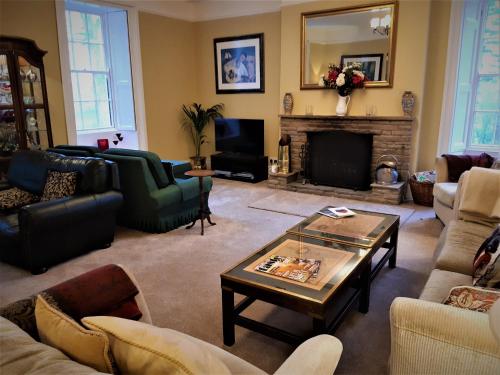 uma sala de estar com mobiliário e uma lareira em Lowbyer Manor Country House em Alston