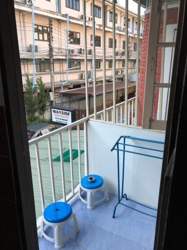 a balcony with two stools and a view of a building at Wayside Guesthouse in Chiang Mai