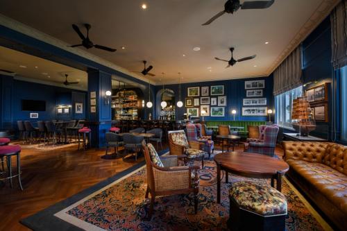 a living room with a couch and tables and chairs at Eastern & Oriental Hotel in George Town