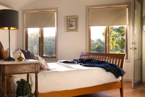 a bedroom with a bed and two windows at Kookaburra Ridge in Hepburn