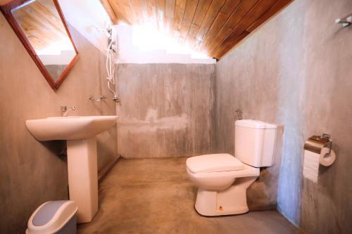 a bathroom with a toilet and a sink at Paper Moon Kudils in Arugam Bay