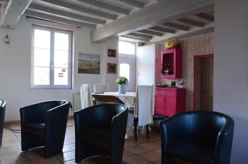 una cocina con sillas negras, una mesa y armarios rosas en La Ferme Pillet, en Berville