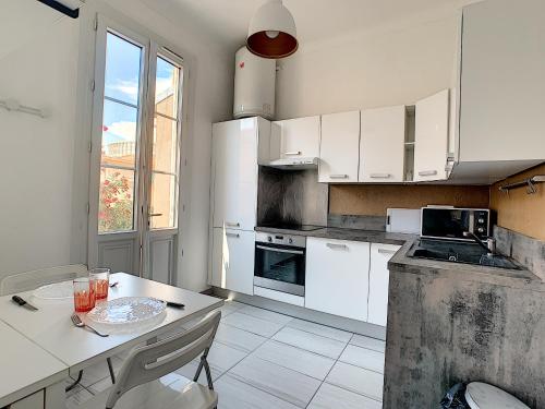 a kitchen with white cabinets and a table with glasses on it at STUDIO NICE in Nice