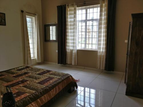 um quarto com uma cama e 2 janelas grandes em Robin Woods Homestay em Sakleshpur