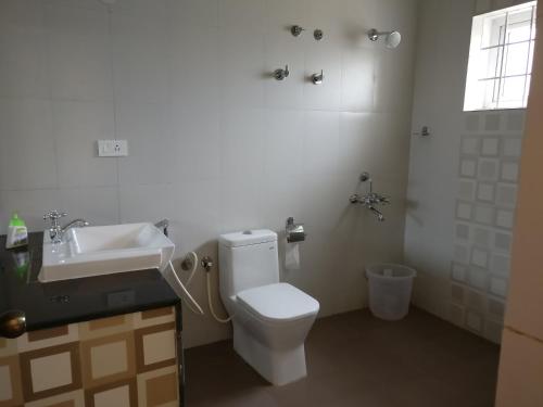 uma casa de banho com um WC branco e um lavatório. em Robin Woods Homestay em Sakleshpur