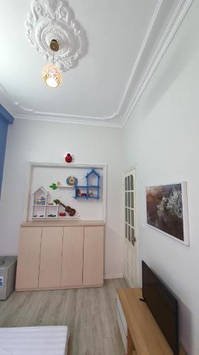 a white living room with a chandelier and a kitchen at De Studio HomeStay in Hanoi