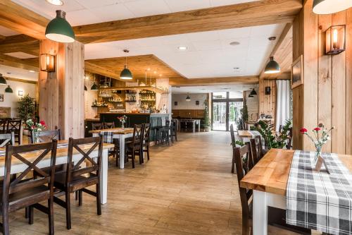 un restaurante con suelo de madera, mesas y sillas en Hotel Helios en Zakopane