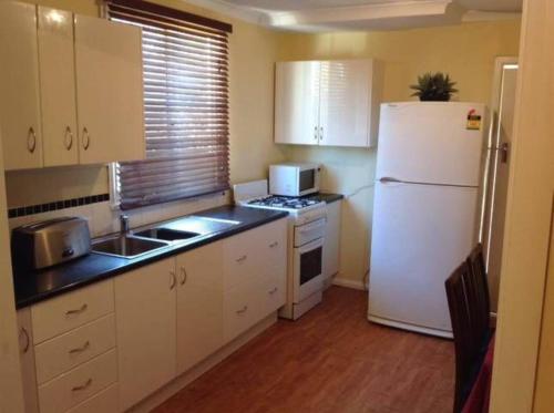 uma pequena cozinha com um frigorífico branco e um lavatório em Wylie Stays em Wyalkatchem