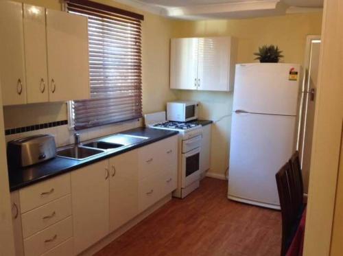 a small kitchen with a white refrigerator and a sink at Wylie Stays in Wyalkatchem