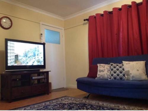 uma sala de estar com um sofá azul e uma televisão de ecrã plano em Wylie Stays em Wyalkatchem