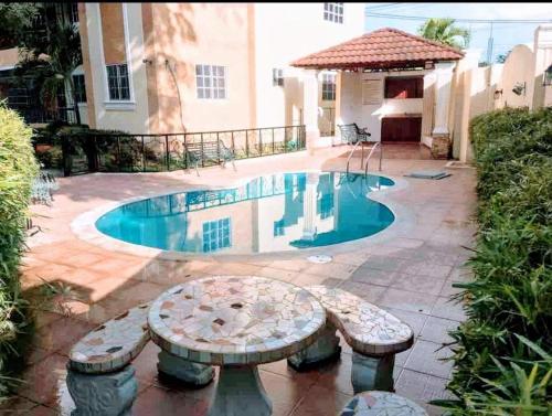 a swimming pool with a bench in front of a house at Total New!! Exclusive!! Apt At Paradise V .. in Santo Domingo