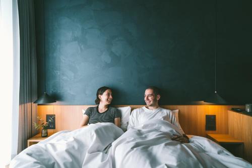 
a man and a woman sitting on a bed at LANDABOUT TOKYO in Tokyo
