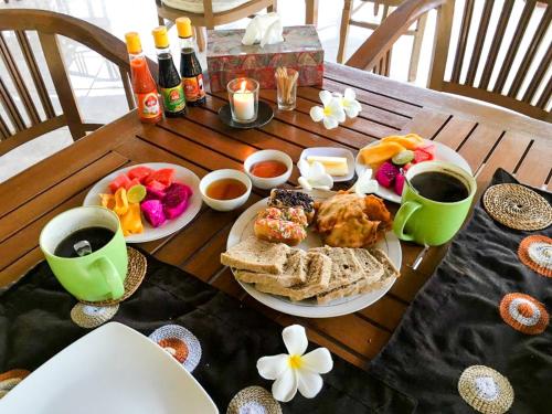 a wooden table with breakfast foods and drinks on it at Bali Oase Resort in Pemuteran