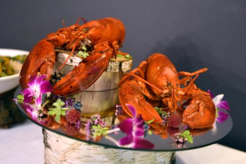 two lobsters in a bucket on a table with flowers at Hotel Grzegorzewski in Tuszyn