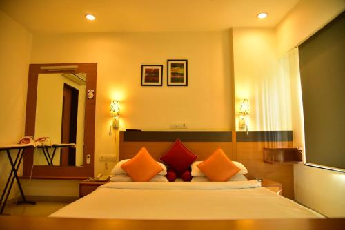 a bedroom with a large bed with orange pillows at Hi 5 Hotel & Experience in Nashik