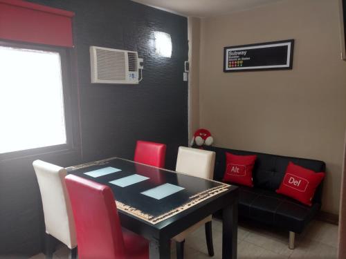 comedor con mesa negra y sillas rojas en Hermoso departamento para viajeros en San Fernando