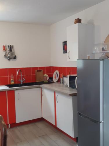 a kitchen with red and white cabinets and a refrigerator at La caz l écho in Cilaos