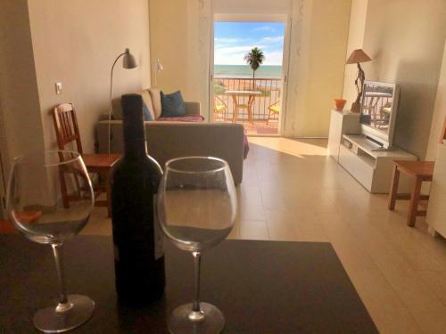 a bottle of wine and two wine glasses in a living room at Frente al mar 1ª línea de playa in Conil de la Frontera