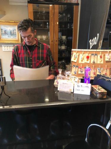 a man standing behind a counter in a store at Guest house daisho oshiro asobi in Matsue