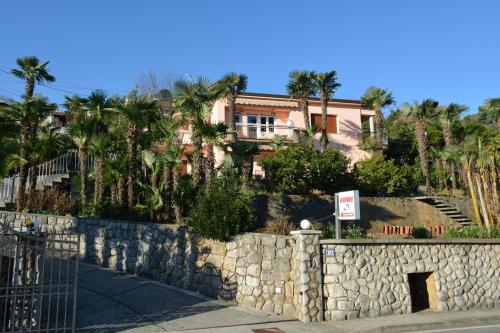 a house behind a stone wall with palm trees at Apartment Valentina in Opatija