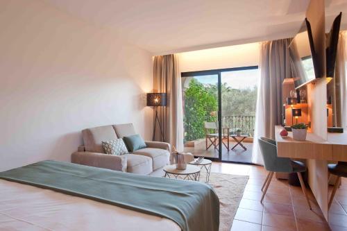 a room with a bed and a living room with a couch at Mon Port Hotel & Spa in Port d’Andratx