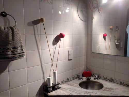 a bathroom with a sink and a mirror and red flowers at Hermoso departamento para viajeros in San Fernando