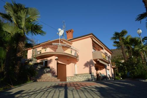 a pink house with a balcony and palm trees at Apartment Valentina in Opatija