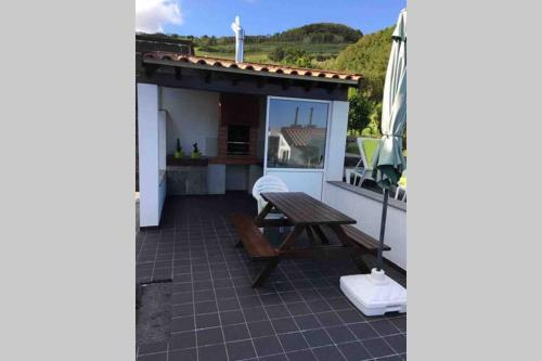 a patio with a bench and a table on a house at Summer house with BBQ and Garden in Horta