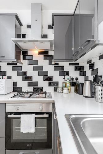 a kitchen with black and white tiles on the wall at WelcomeStay Clapham Junction 2 Bedroom Apartment in London