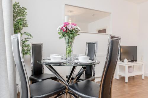 a dining room table with chairs and a vase of flowers at WelcomeStay Clapham Junction 2 Bedroom Apartment in London