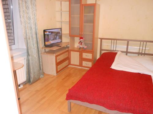 1 dormitorio con cama roja y TV en Apartaments LiS 2, en Peterhof