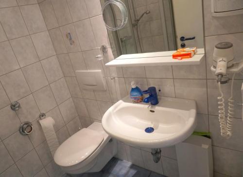 ein Badezimmer mit Waschbecken, Toilette und Spiegel in der Unterkunft Zentrales Apartment für 2 *Bogenstraße* in Norderney