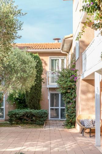 a building with a balcony and a bench in a courtyard at Best Western Plus Hyères Côte D'Azur in Hyères