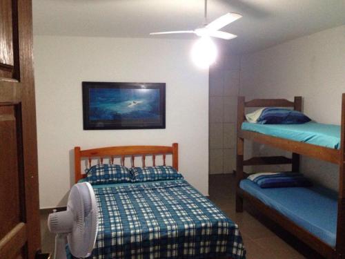 a bedroom with two bunk beds and a ceiling fan at Coqueiros Praia Martin de Sá in Caraguatatuba