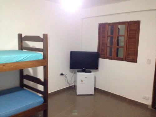 a room with two bunk beds and a television at Coqueiros Praia Martin de Sá in Caraguatatuba