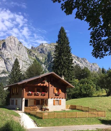 a house in a field with mountains in the background at B&B Casa PerAria in Paluzza