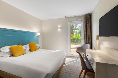 a hotel room with a bed and a desk and a window at Best Western Plus Hyères Côte D'Azur in Hyères