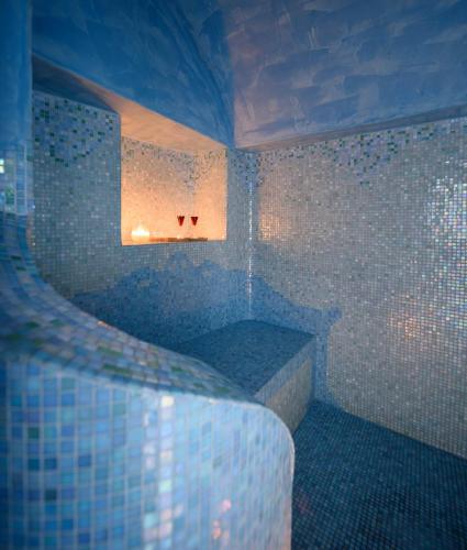 a bathroom with a tub with blue tiles on the wall at Above Blue Suites in Imerovigli
