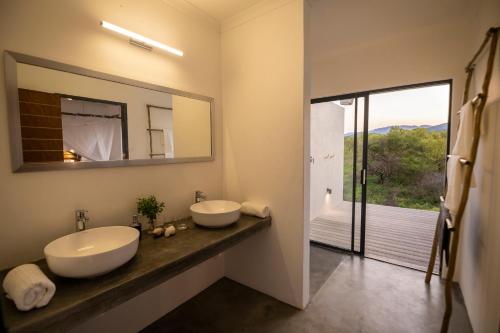 a bathroom with two sinks and a large mirror at Kruger Cliffs Lodge - Absolute privacy guaranteed in Hoedspruit