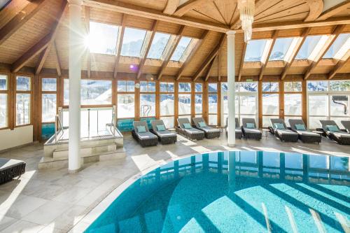 une piscine dans un bâtiment avec des chaises et une piscine dans l'établissement Haller's Geniesserhotel, à Mittelberg