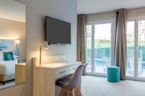 a bedroom with a desk with a television and a bed at Best Western Plus Hyères Côte D'Azur in Hyères