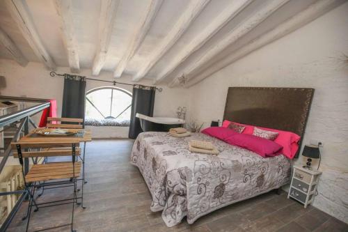 Un dormitorio con una cama con almohadas rosas y una mesa. en Cabana del Tio Pepe, en Ainzón