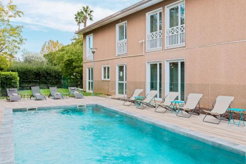 a swimming pool with chairs and a building at Best Western Plus Hyères Côte D'Azur in Hyères