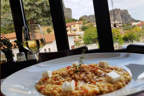 a plate of food on a table with a glass of wine at Theatro Hotel Odysseon in Kalabaka