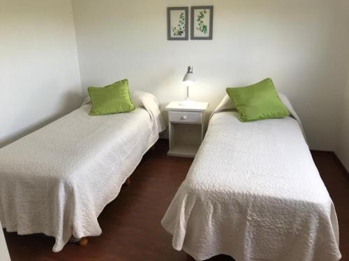 two beds with green pillows in a room at Alquiler Temporario Los Olivos in Junín