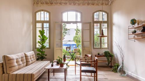 a living room with a couch and tables and windows at Ruby in Tel Aviv