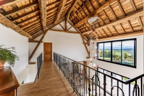 a staircase in a house with wooden ceilings and windows at Gîte et chambres d'hôtes - La Maison du Grand Bossieu in Bossieu