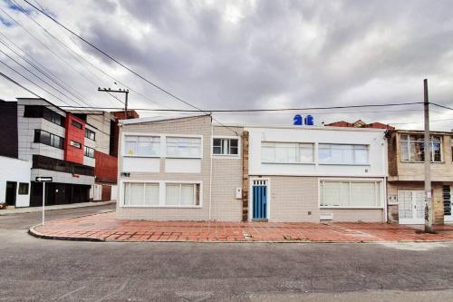 une maison blanche avec une porte bleue dans une rue dans l'établissement HOMY APARTAMENTOS - Corferias, embassy, airport, G12, UN, Agora, à Bogotá